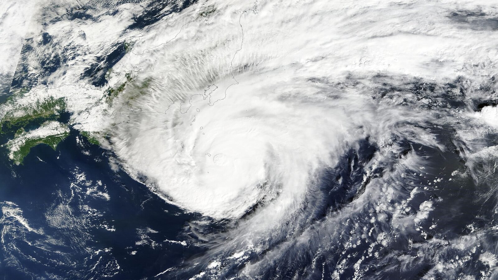 Thematic lead image: flooded street, heavy rain, airport disruption — Japan's Infrastructure Stress Test: Beyond the Local Deluge | National Times